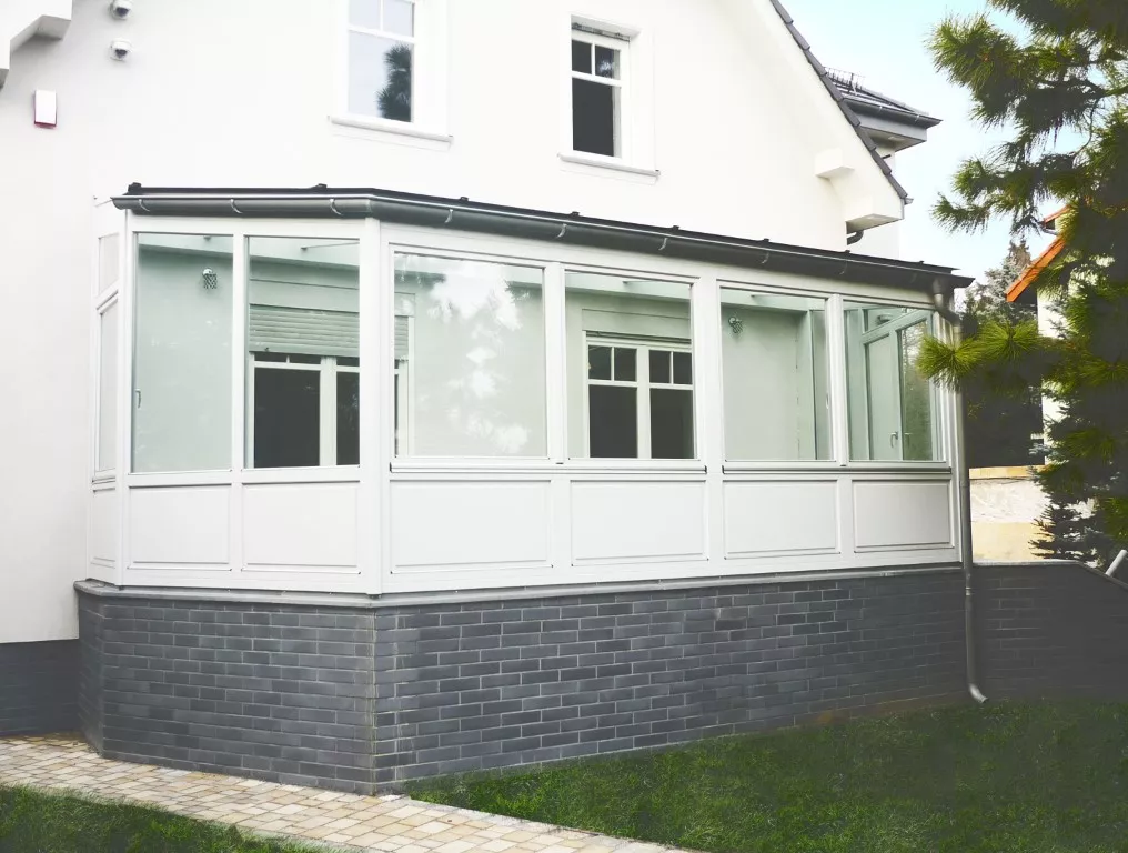 Ogród zimowy z drewnianymi białymi oknami